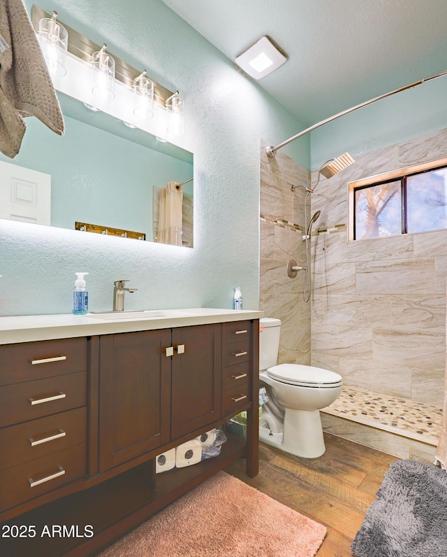 bathroom featuring toilet, hardwood / wood-style floors, vanity, and walk in shower