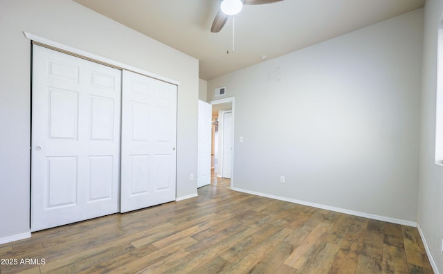 unfurnished bedroom with dark hardwood / wood-style flooring, a closet, and ceiling fan