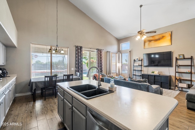 kitchen featuring high vaulted ceiling, ceiling fan with notable chandelier, open floor plan, and a sink