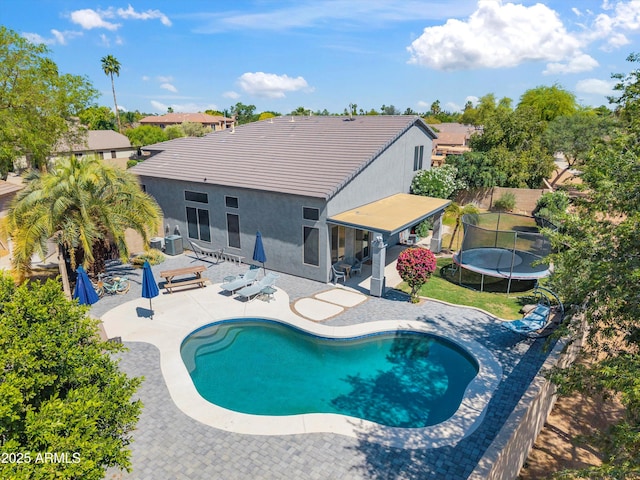 outdoor pool with a fenced backyard, a patio, and a trampoline
