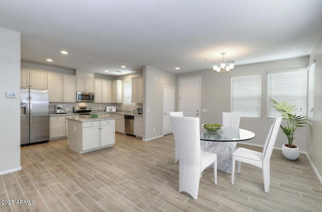 14870 W Encanto Blvd Unit 1106, Goodyear, AZ 85395 - kitchen featuring a kitchen island, stainless steel appliances, baseboards, and a chandelier
