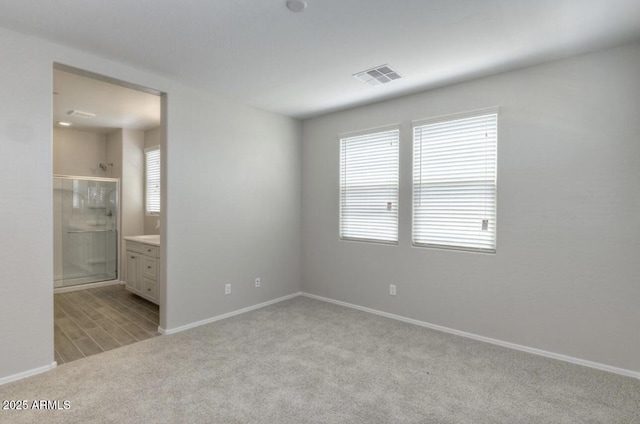 14870 W Encanto Blvd Unit 1106, Goodyear, AZ 85395 - unfurnished bedroom featuring baseboards, light carpet, connected bathroom, and visible vents