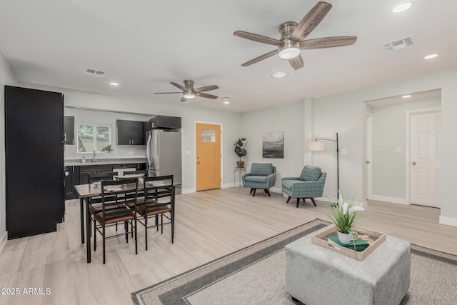 living room with ceiling fan, sink, and light wood-type flooring