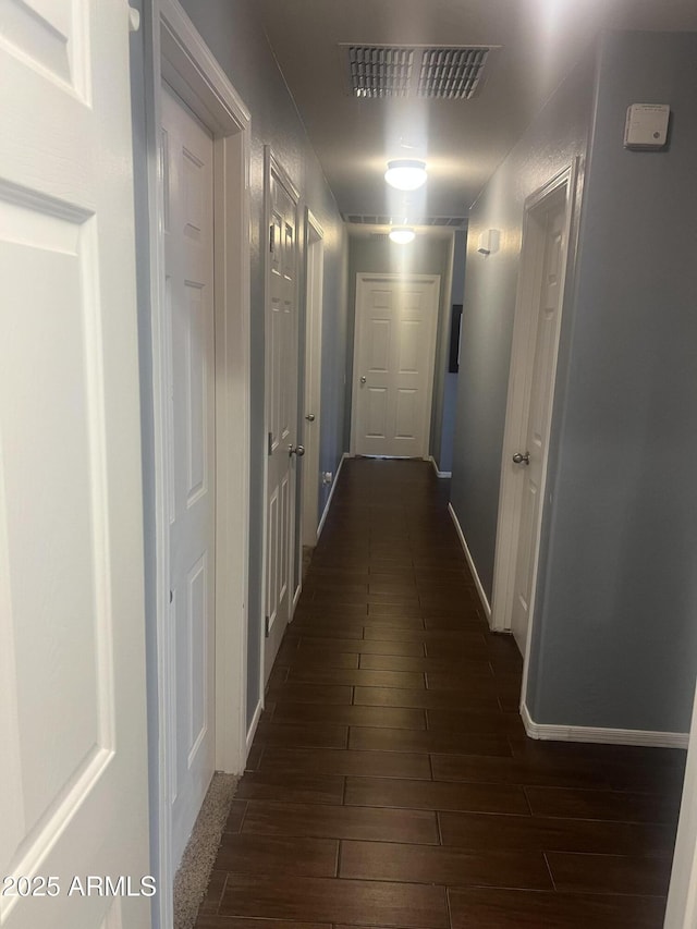 hallway with baseboards, dark wood-style floors, and visible vents