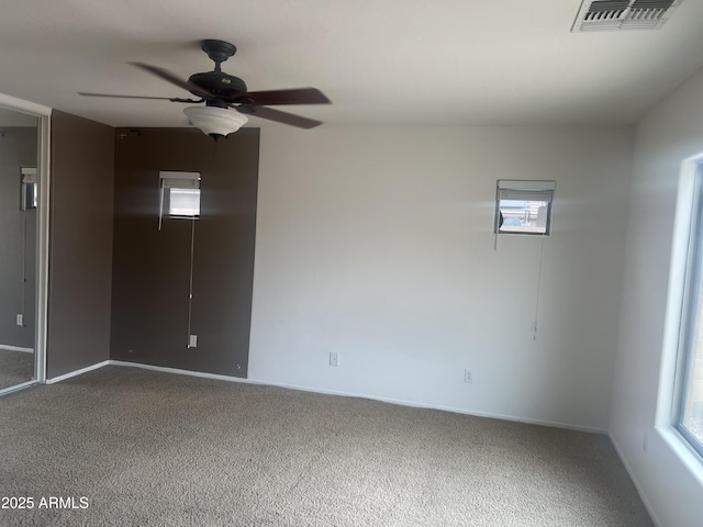 spare room featuring carpet flooring, visible vents, baseboards, and a ceiling fan