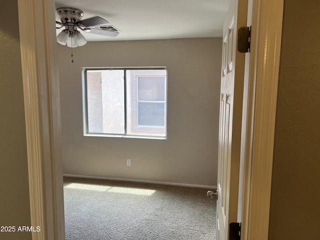 carpeted empty room with baseboards and a ceiling fan
