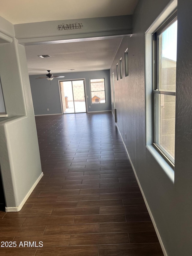 hall featuring baseboards, visible vents, and dark wood finished floors