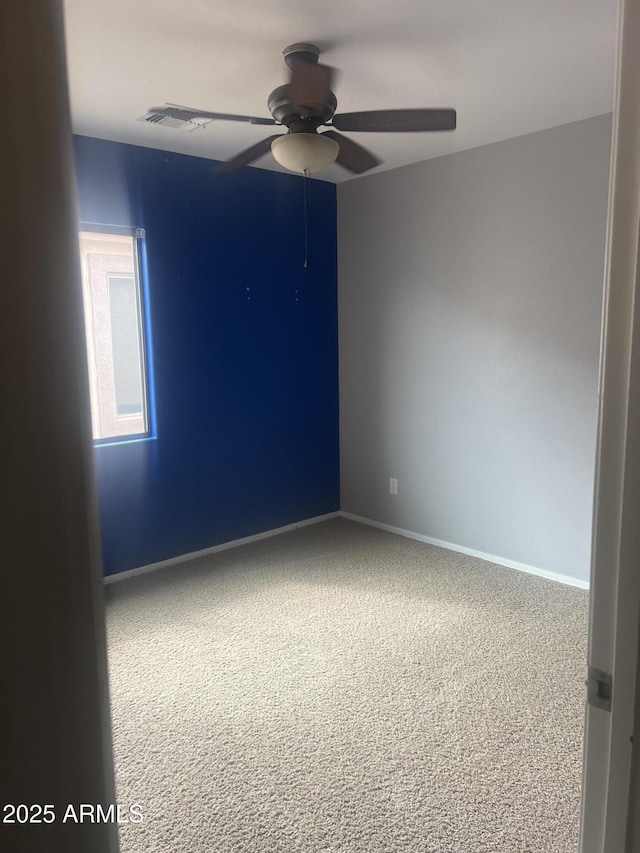 carpeted empty room featuring visible vents, baseboards, and a ceiling fan