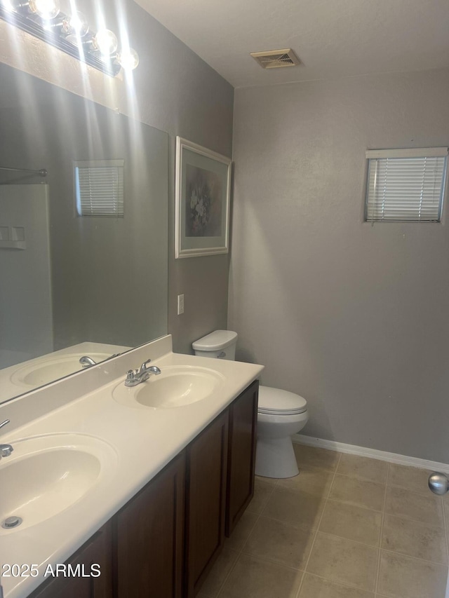 bathroom featuring toilet, visible vents, a sink, and double vanity