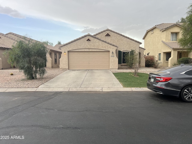 view of front facade with a tile roof, a garage, stucco siding, and driveway