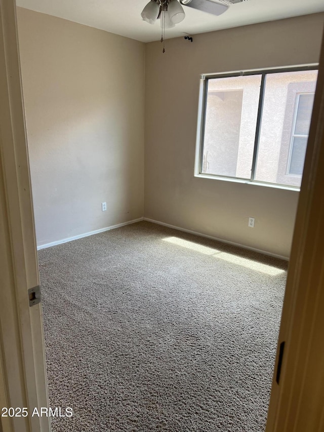 carpeted empty room with a ceiling fan and baseboards