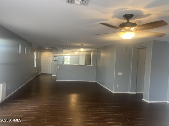unfurnished room featuring baseboards, ceiling fan, visible vents, and dark wood-type flooring