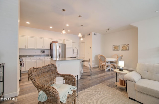 living area with baseboards, recessed lighting, wood finished floors, and visible vents