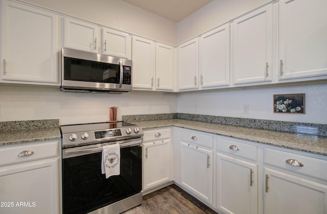 kitchen featuring light stone counters, white cabinets, stainless steel appliances, and dark wood-type flooring