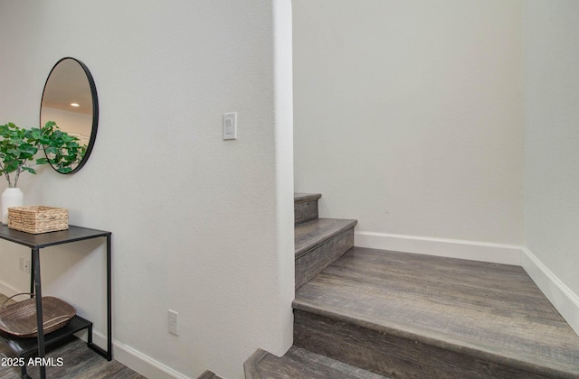 staircase featuring baseboards and wood finished floors