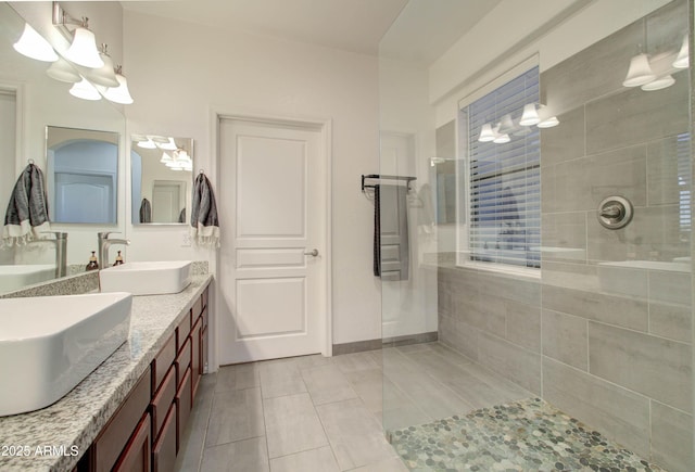bathroom featuring a walk in shower, a sink, tile patterned flooring, double vanity, and a chandelier