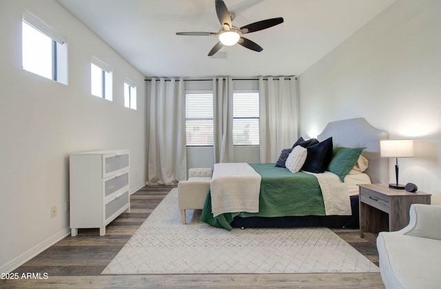 bedroom with dark wood-type flooring, a ceiling fan, and baseboards