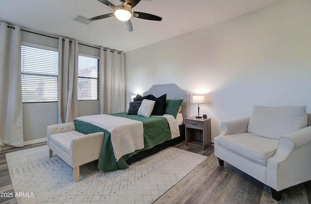 bedroom with a ceiling fan, wood finished floors, and visible vents