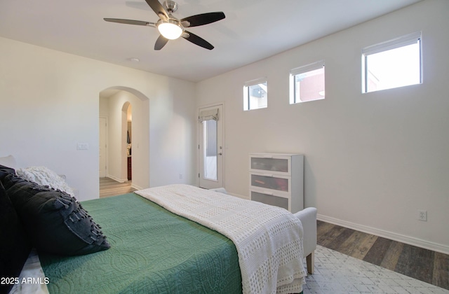 bedroom featuring arched walkways, baseboards, ceiling fan, and wood finished floors
