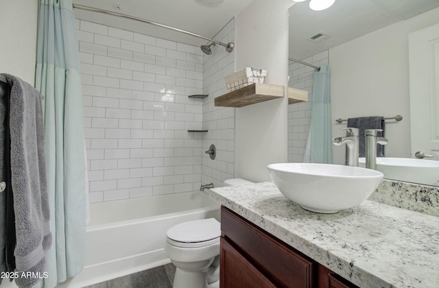 bathroom with visible vents, vanity, wood finished floors, shower / bath combination with curtain, and toilet
