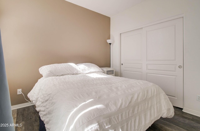 bedroom with baseboards, dark wood finished floors, and a closet