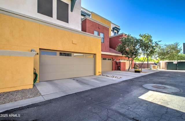 view of side of home with stucco siding, concrete driveway, and a garage