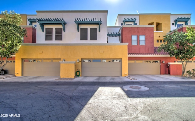 view of property with an attached garage, stucco siding, and driveway