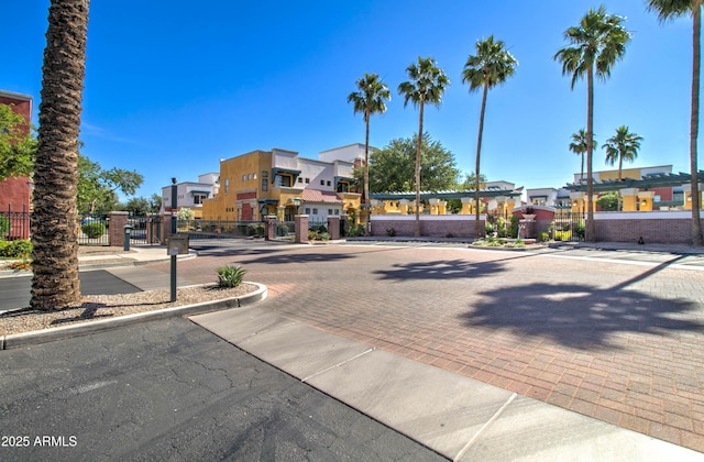 view of road with curbs, a gated entry, a residential view, a gate, and sidewalks