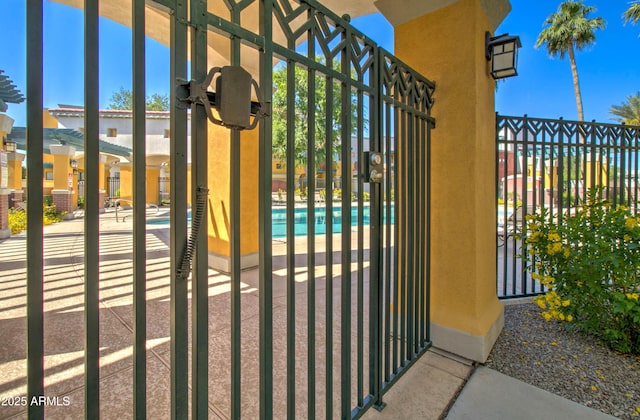 view of gate with a community pool, a patio area, and fence