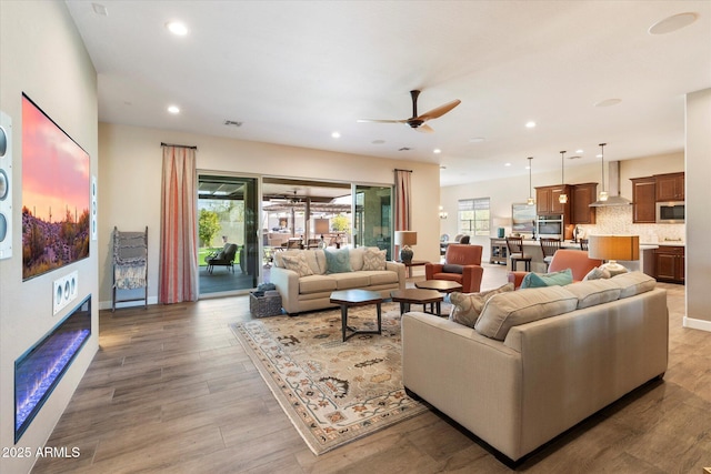 living room with light hardwood / wood-style flooring, a wealth of natural light, and ceiling fan