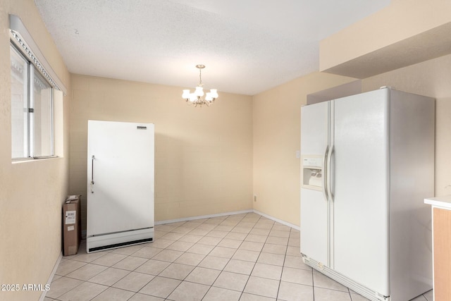 kitchen featuring light tile patterned floors, freestanding refrigerator, an inviting chandelier, white fridge with ice dispenser, and a textured ceiling