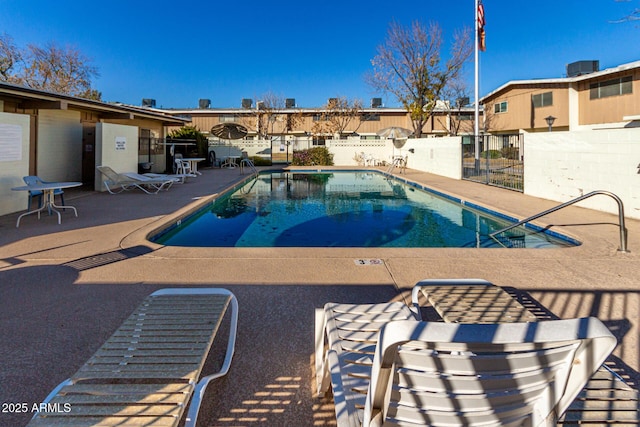 pool with a patio and fence