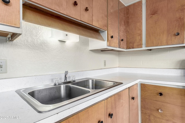 kitchen featuring light countertops, brown cabinets, and a sink