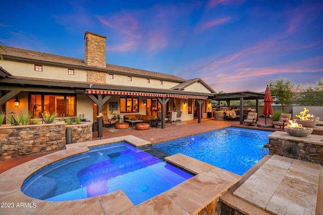 pool at dusk featuring a fire pit, a gazebo, an in ground hot tub, and a patio area