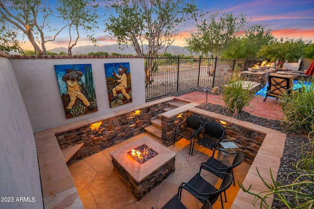 patio terrace at dusk featuring a fire pit and a mountain view