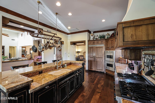 kitchen featuring sink, a large island, light stone countertops, crown molding, and dark hardwood / wood-style flooring