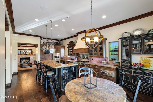 kitchen with pendant lighting, a kitchen island with sink, dark hardwood / wood-style floors, a notable chandelier, and a kitchen bar