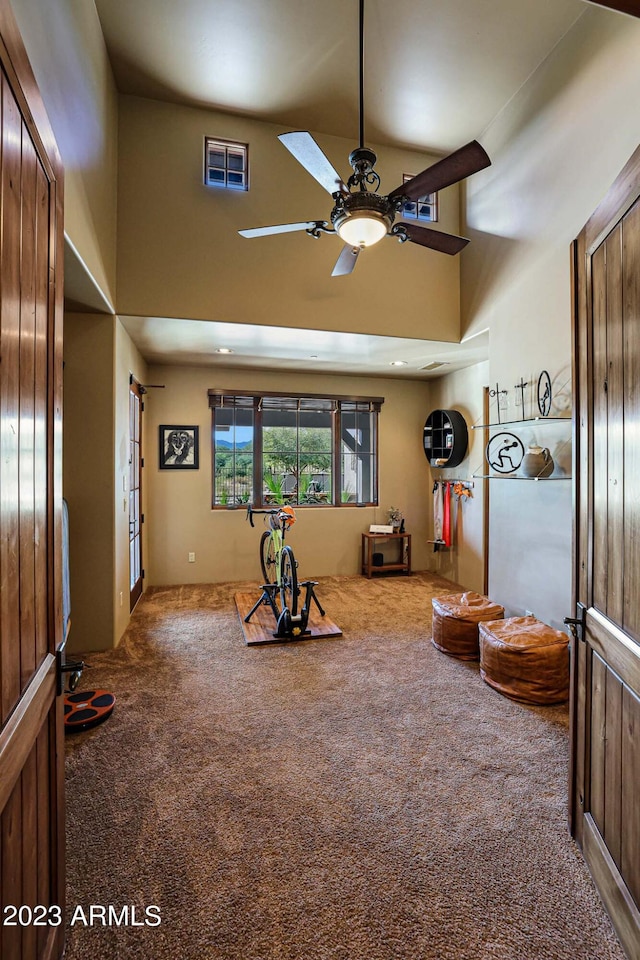 interior space featuring carpet, a towering ceiling, and ceiling fan