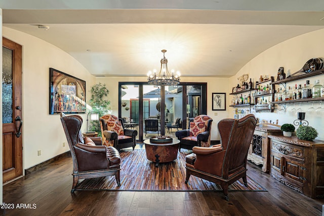 living room with a notable chandelier, vaulted ceiling, bar area, and dark wood-type flooring