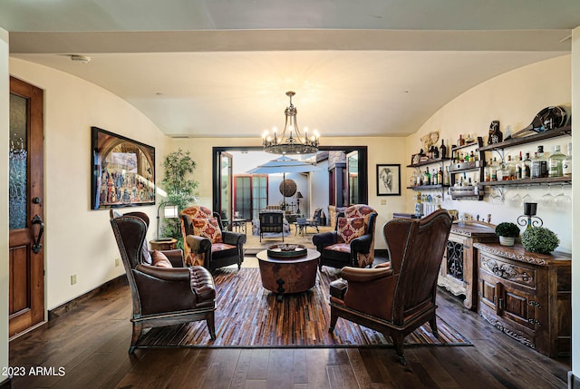 living room featuring bar, lofted ceiling, dark wood-type flooring, and a notable chandelier