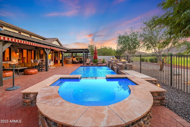 pool at dusk with a patio and an in ground hot tub