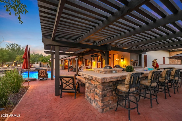 patio terrace at dusk with a bar and a pergola