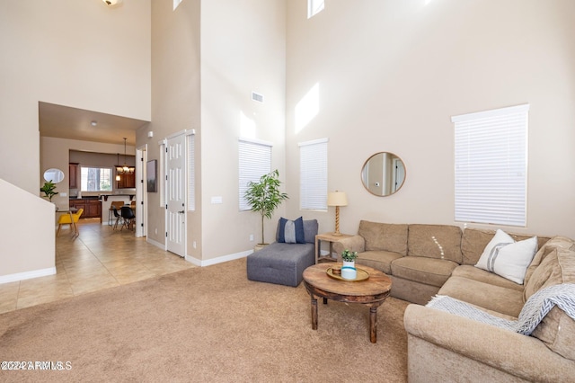 living room featuring light carpet, a high ceiling, and an inviting chandelier