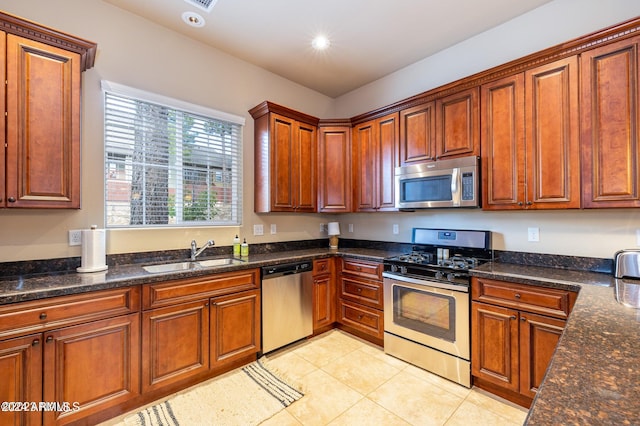 kitchen featuring light tile patterned flooring, appliances with stainless steel finishes, sink, and dark stone counters