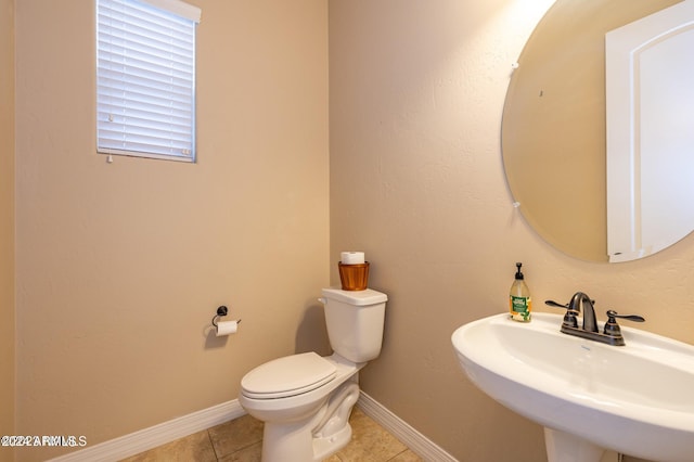 bathroom featuring toilet, sink, and tile patterned flooring