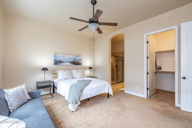 bedroom featuring light carpet, ceiling fan, and ensuite bath