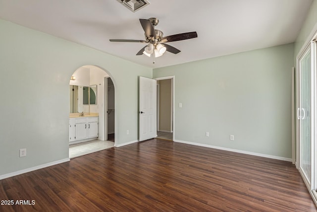 4845 W Evans Dr, Glendale, AZ 85306 - unfurnished bedroom featuring arched walkways, wood finished floors, ensuite bath, and ceiling fan