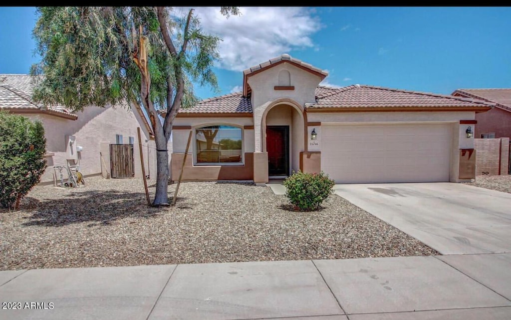 mediterranean / spanish-style home featuring an attached garage, fence, driveway, a tiled roof, and stucco siding