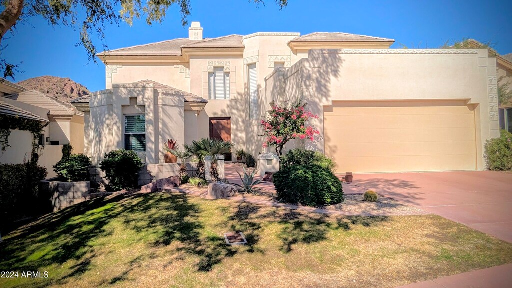 pueblo-style house with a garage and a front lawn