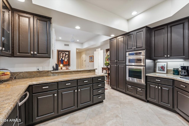 kitchen featuring light stone counters, double oven, and dark brown cabinets